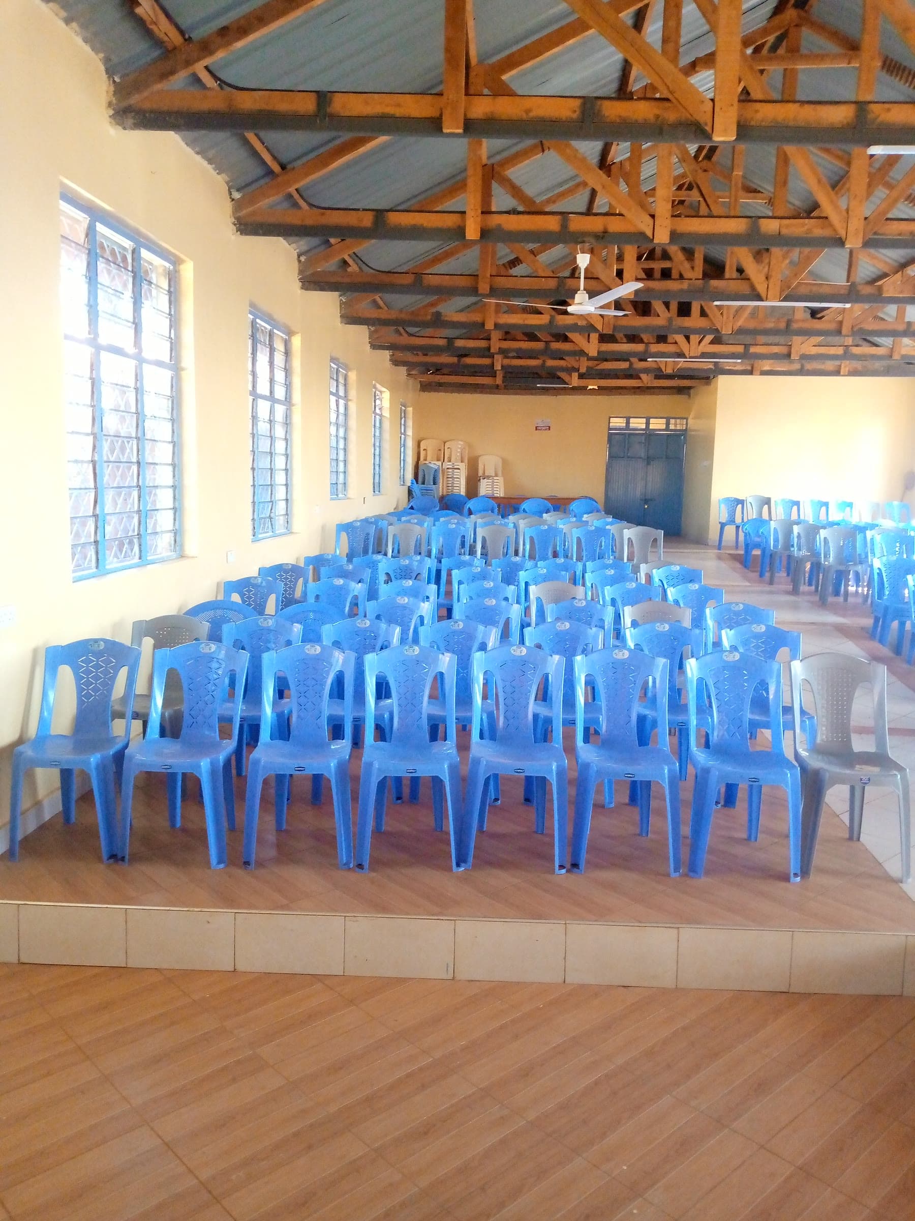 Exposed timber trusses above rows of blue chairs